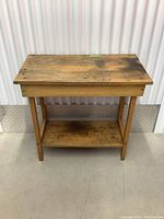 Front view of the rustic wooden accent table showing top surface and bottom shelf with visible wear and discoloration.