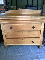 Front view of the vintage maple dresser showing the three drawers, finish, and partial knobs.