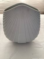 Front view showing white porcelain vase with radiating ribs and oval top opening.