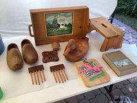 All items arranged on table, showing general lot contents including wood tray, carved duck, shoe form, step stool, combs, trivet, notepad plaque, and book.