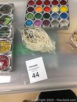 Top view of tray holding multiple tins of seed beads in assorted colors, strings of glass pearls, and other bead containers