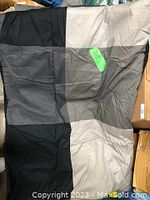 Folded queen size comforter with color block pattern in black, gray, and beige tones, displayed flat to show pattern.