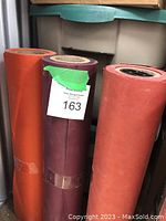 Three partial rolls of butcher paper in different colors photographed upright against a shelf with a number 163 label.