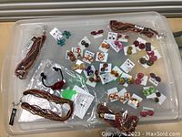 Top view of assorted costume jewelry laid out on plastic tub including earrings on cards and beaded chokers in clear plastic bags.