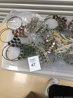 Top view of assortment of costume jewelry including bracelets and necklaces spread over a plastic surface.