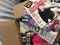 Opened box showing several vintage craft magazines partially visible with cover titles related to needlework and knitting.