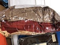 Curtain fabric samples stacked and wrapped in plastic including brown and red colors.