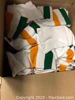 Box filled with white hockey socks with green and gold stripes scattered inside.