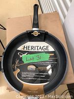 Top view of the Heritage Artisan 12.5 inch cast aluminum pan showing the handle and pan interior with packaging label visible
