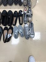 Photo showing multiple pairs of women’s shoes including sneakers, boots, flats in colors black, gray, and taupe.