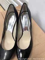 Top view of Michael Kors black patent leather shoes showing brand label inside and overall condition.
