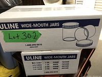 Two stacked Uline boxes labeled 'Wide-Mouth Jars' with the lot number and quantity information visible.