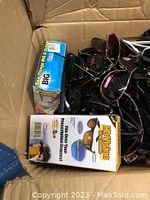 Box full of multiple assorted sunglasses and two eyewear items in boxes, showing variety and quantity.