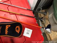 Golf clubs arranged showing shafts and heads including a Jr. Mojo club with orange shaft.