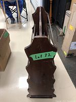 Full side view of vintage wooden magazine rack showing scalloped side panel and dark wood finish.