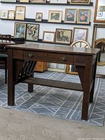 Front angled view of the antique oak desk showing the main drawer and side panel design.