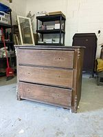 Front view of three-drawer wooden dresser with removed drawer pulls and prepped surface.