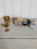 Photo showing entire collection of three mouse figures, furniture, TV, and picture frames on a white surface with a white panel background.