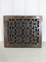 Front view of metal vent cover showing its intricate geometric grid design and mounting holes.
