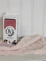 Photo of The OVer Company Over Cover packaging in mauve/pink alongside a soft light pink handmade lovie blanket.