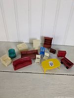 Photo showing all plastic dollhouse furniture pieces arranged on floor against white paneled wall.