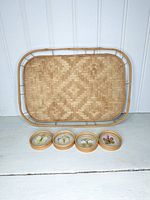 Rattan rectangular tray with four round coasters arranged in front showing floral designs.