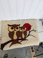 Full view of handcrafted hooked rug showing three brown owls on a branch with a red sun/moon behind them.