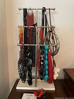 Photo of various necklaces displayed on a two-tier metal necklace stand including natural stone and beaded necklaces in different colors and styles.