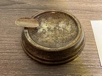Top view of tarnished sterling silver ashtray with cigarette rest on a wooden surface.