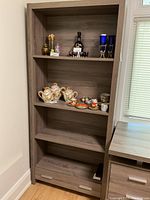 Front view of IKEA shelving unit filled with decorative items including teapots, cups, glassware.