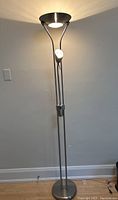 Front view of the modern floor lamp turned on showing the uplight and articulating reading arm light illuminated.