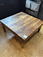 Angled view showing the top wood grain, metal fasteners, and metal detailing on sides of the coffee table.