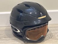 Side view of black Giro snowboarding helmet with Oakley goggles showing helmet vents and branded goggles strap.
