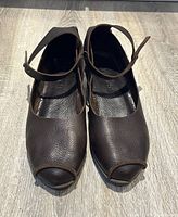 Front view of both brown pebbled leather shoes with open toes and ankle straps, showing good condition.