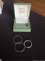 Two 14K gold hoops and one twisted 10K earring shown with Astor 14K Gold jewelry box.