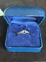 Ring shown inside blue ring box resting on blue velvet cushion.