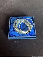 Three sterling silver bracelets displayed inside a small blue box with blue satin lining.