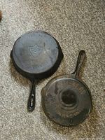 Two antique cast iron frying pans on carpet, one labeled CSW Made in Canada No. 8, other labeled Finolay Carleton Place Ont No. 6, showing overall condition and markings.