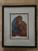 Front view of the professionally framed and matted print depicting Indigenous mother and child artwork in warm colors.