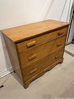 Front view showing three drawers with wooden handles and the overall shape of the antique pine dresser.