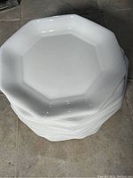Stack of white geometric octagonal plates showing the top plate and the profile of the stacked plates.