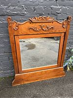 Full view of the antique wooden framed mirror, showing rectangular mirror and carved wood frame with floral and scroll elements.