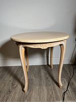 Full side view showcasing the faux marble lacquered round top, carved apron and curved wooden legs with ornamental detail.