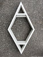 Front view of the wooden diamond-shaped necklace display stand lying on pavement, showing overall shape and condition.