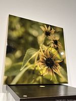 Front view of the painted resin flower art on a wood board showing the yellow flowers and greenish background with glossy surface.
