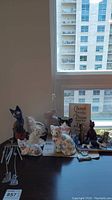 Wide view of all cat figurines and the white rabbit figurine arranged on a dark surface by the window.
