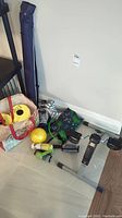Photo showing a small collection of exercise items including a pedal exerciser, hand weights, resistance bands, hot/cold bag, exercise mat in a bag, and a small carrying bag.
