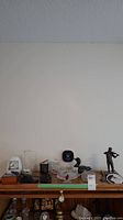 Photo showing all items together on a shelf: Irish fiddler figurine, wood loon sculpture, small glassware, illuminated wolf, crucifix, carved wood faces, stained resin hummingbird