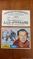 Front side of the signed hockey card featuring Alex Delvecchio in Detroit Red Wings uniform and his autograph in blue ink.