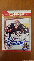 Front of signed Brian Elliott hockey card showing player in Ottawa Senators uniform with large blue autograph.